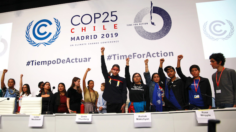 An image of a group of students posing by a backdrop for COP 25 conference Madrid, 'time for action - Climate Change'