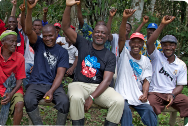 Image taken from the Karma Drinks website. Sierra-Leone farmers raising their fists in the air of celebration, sporting Karma Drinks merchandise.