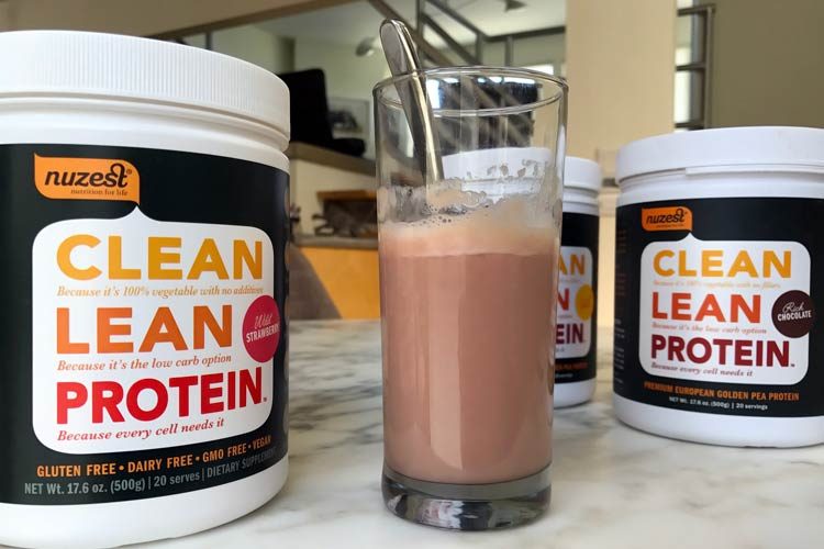 My favourite clean lean protein flavours are strawberry and chocloate - Image of a pot of chocloate protein with a milkshake