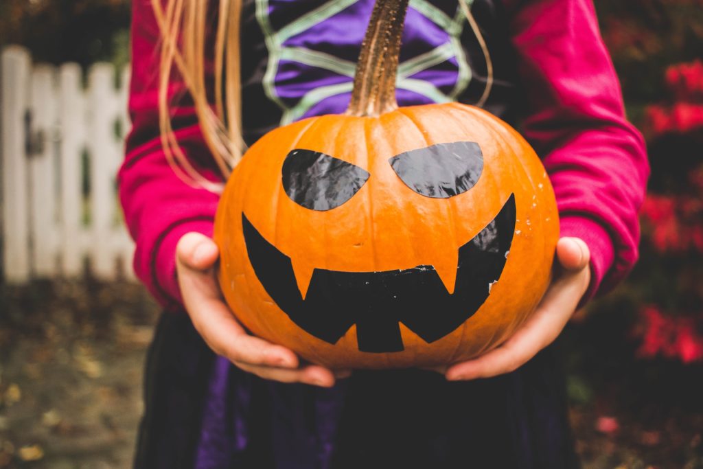 Girl holding carved pumpkin with stickers CREDIT Unsplash